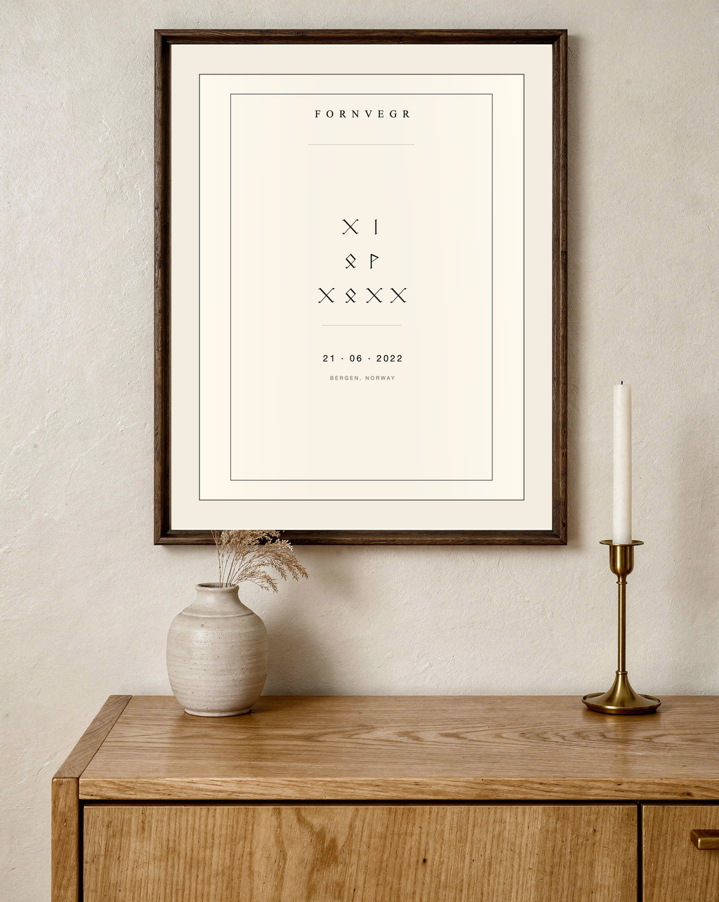Runic birth marker in a dark wood frame above an oak sideboard with a candle and vase