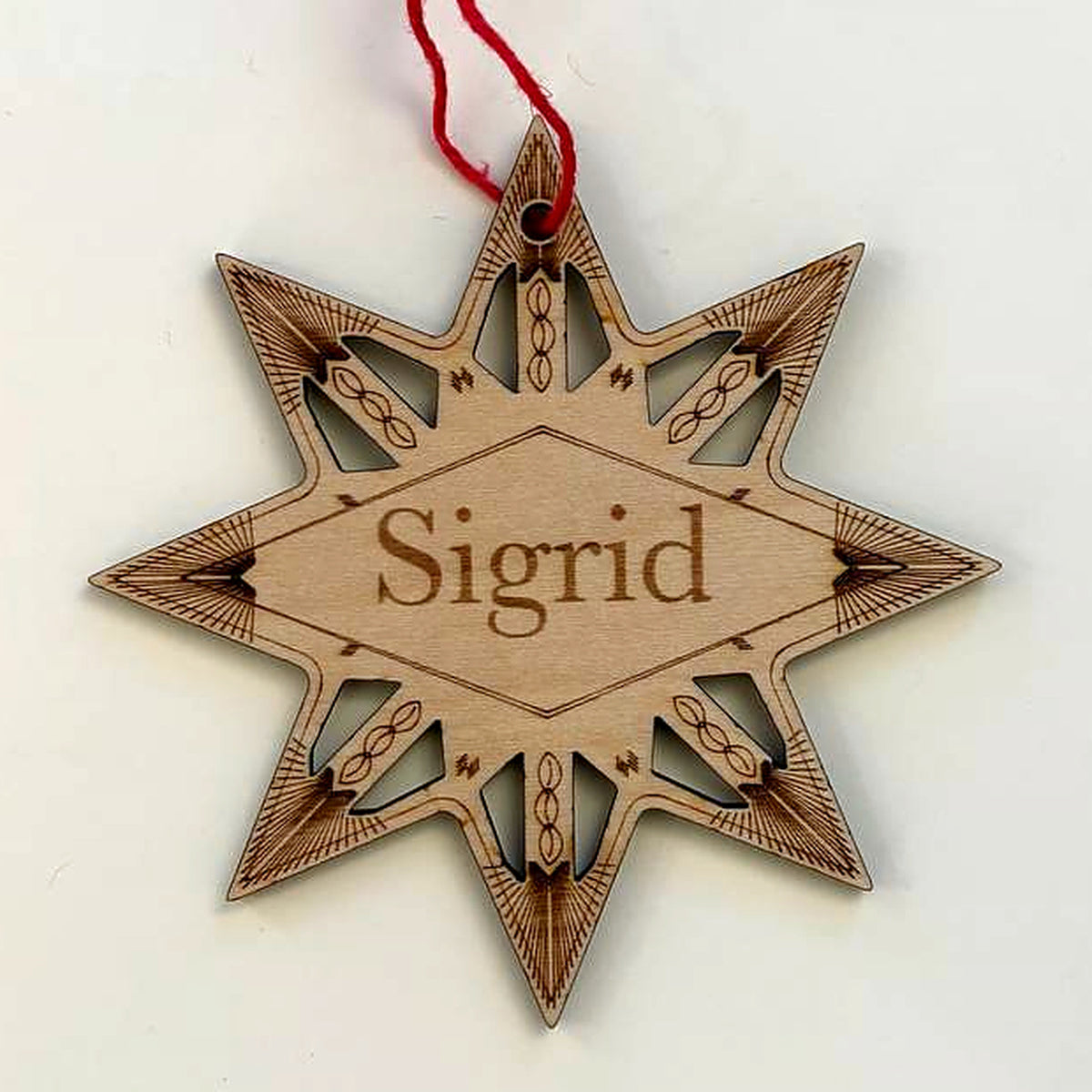 Close view of the winter star ornament: the engraved name Sigrid framed by cut-out star points and engraved details