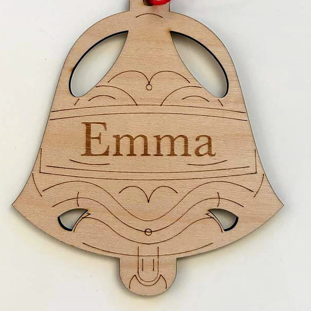 Close view of the winter bell ornament: the engraved name Emma on a wide band with engraved scrollwork